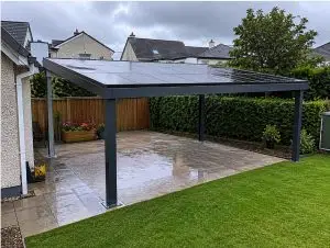 Solar carport with dark panels over a patio and lawn at an Irish home